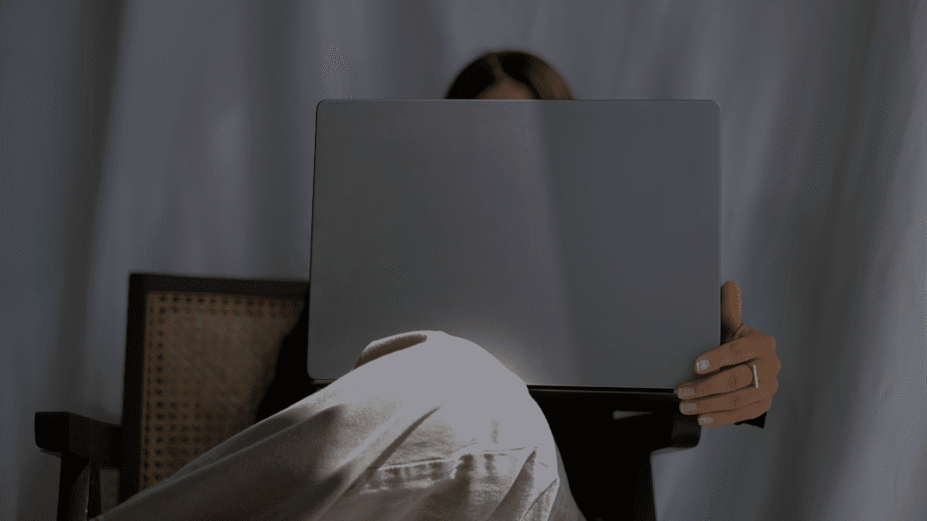 Junge Frau sitzt hinter einem Laptop, anonym dargestellt – symbolisiert Arbeiten am Notebook