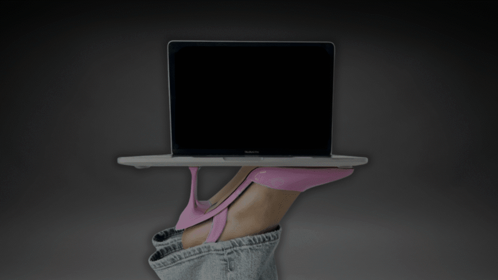 Offener MacBook, gehalten von rosa offenen, hochhackigen Frauenschuhen – symbolisiert Frauenpower.